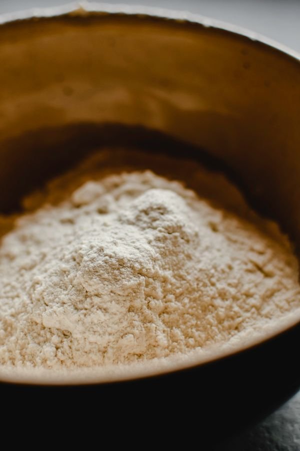 A detailed shot of flour in a rustic brown bowl ideal for baking themes.
